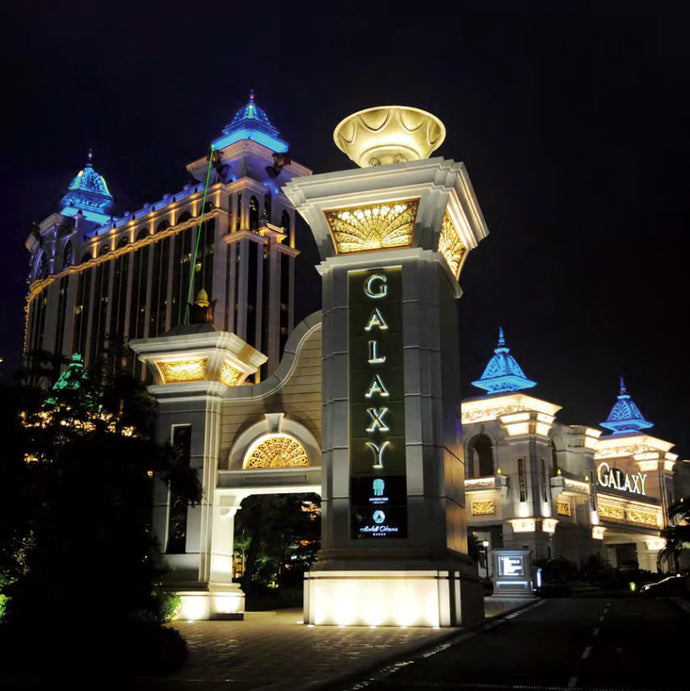 A view of the pillars of the Galaxy Resort, lit up at night.